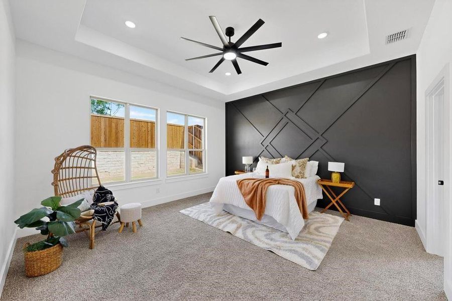 Bedroom with carpet flooring, recessed lighting, a raised ceiling, and an accent wall