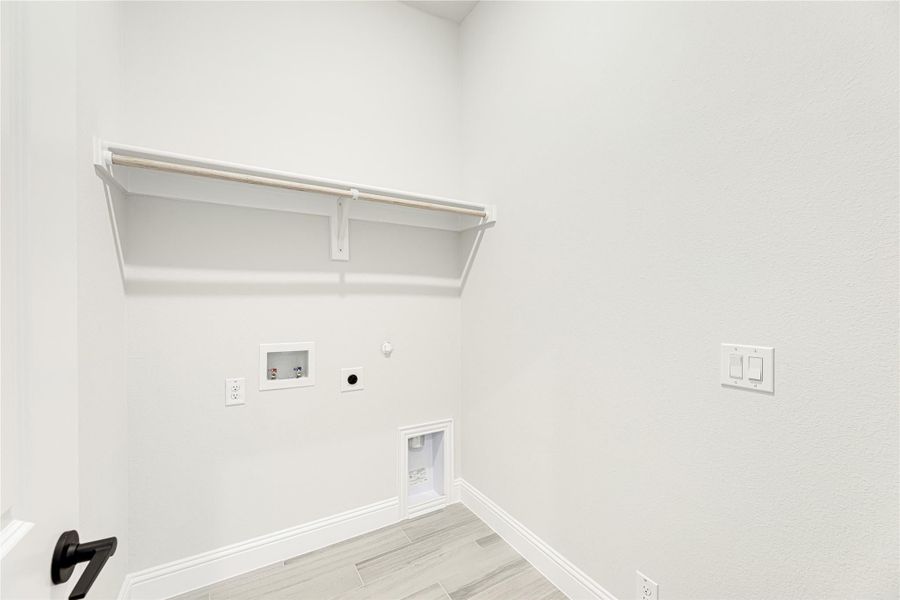 Laundry room with wall-mounted shelf, washer and dryer hookups, and light wood-look tile floor