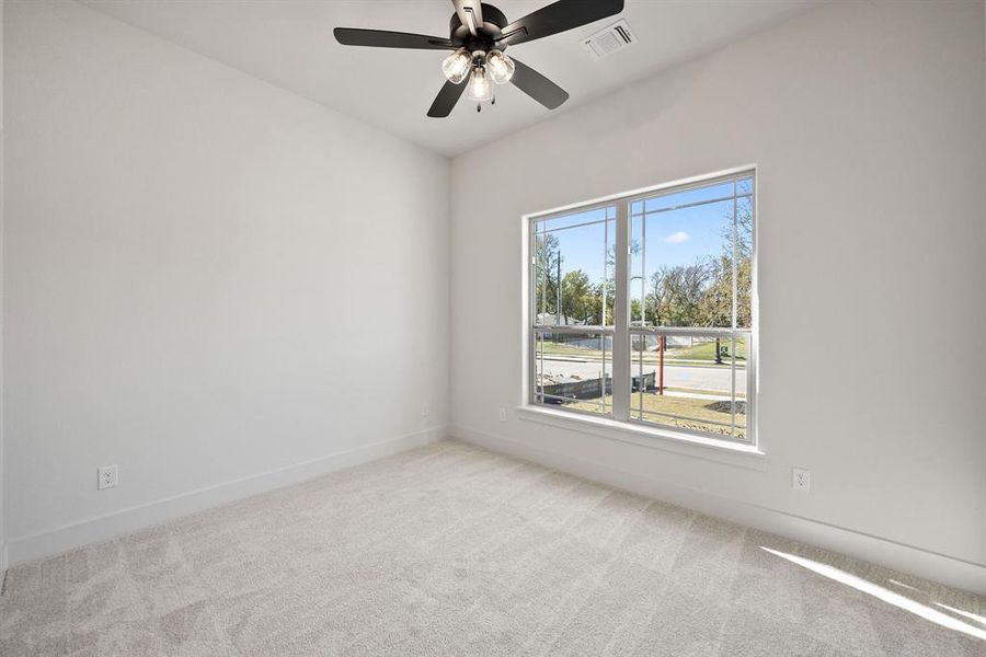 Empty room featuring light carpet and a ceiling fan