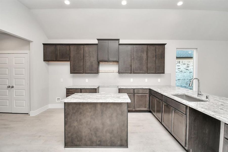 Discover another perspective of this stunning kitchen, generously appointed with an abundance of counter space. Sample photo of completed home. Actual colors and selections will vary.