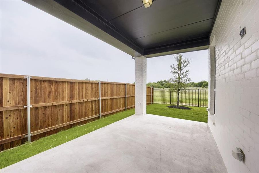 Covered patio with a concrete surface, white painted brick exterior, and a dark soffit