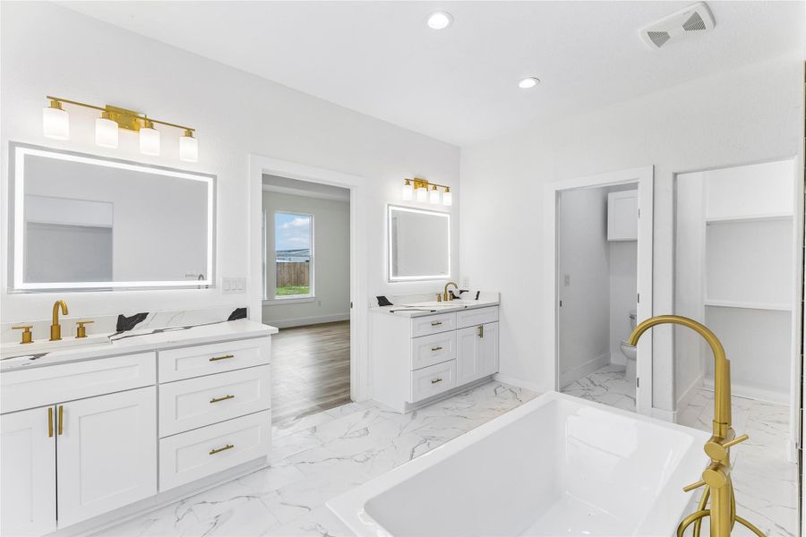 Luxurious primary bath with dual vanities, modern fixtures, and a spacious soaking tub.