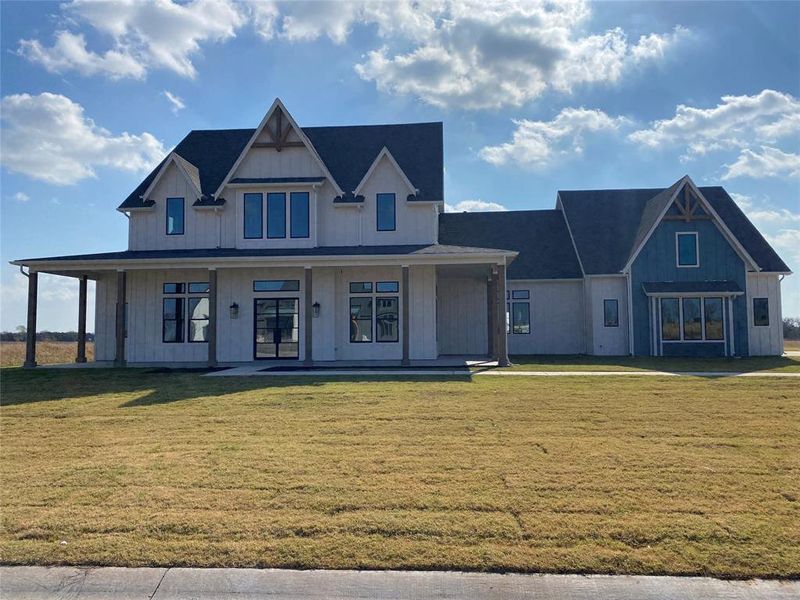 Modern farmhouse style home featuring covered porch, a front lawn, and board and batten siding