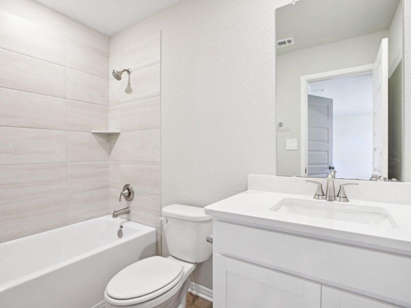 Bathroom with toilet, shower / tub combination, vanity, and a textured wall Bathroom with toilet, shower / tub combination, vanity, and a textured wall