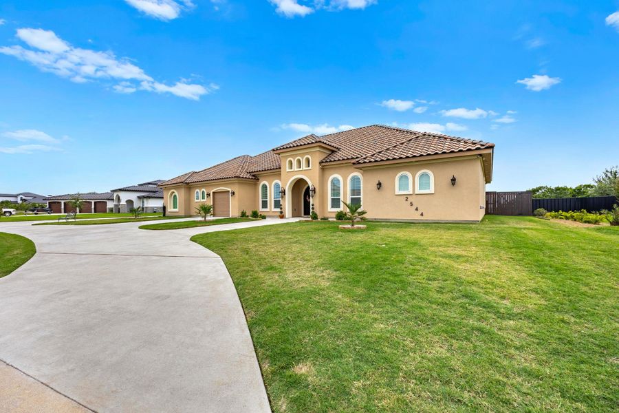 Grand stucco facade with arched windows and a clay tile roof creates an inviting street presence. Grand stucco facade with arched windows and a clay tile roof creates an inviting street presence.