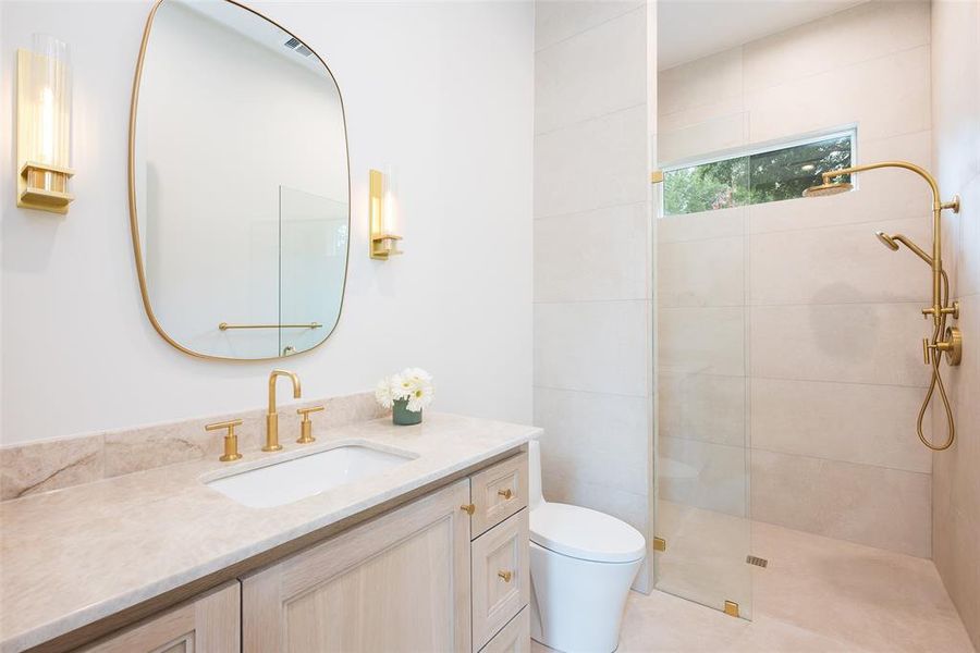 Bathroom with tiled shower, vanity, and toilet