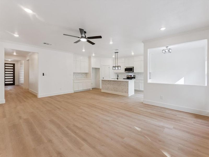 Unfurnished living room with ornamental molding, light wood-type flooring, recessed lighting, and ceiling fan
