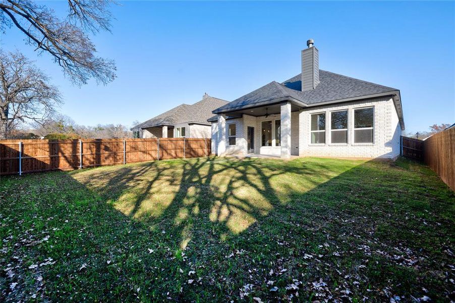 Back of house with ceiling fan and a yard