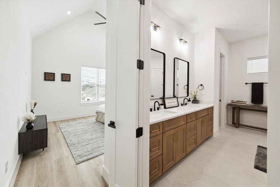 Primary bathroom offers a spacious dual vanity with under-mount sinks, and black faucets. Thoughtfully laid out cabinetry combines drawers with cabinets to leave no space wasted.