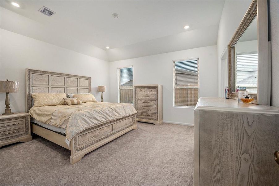 Spacious primary bedroom has cozy carpet and lots of natural light.