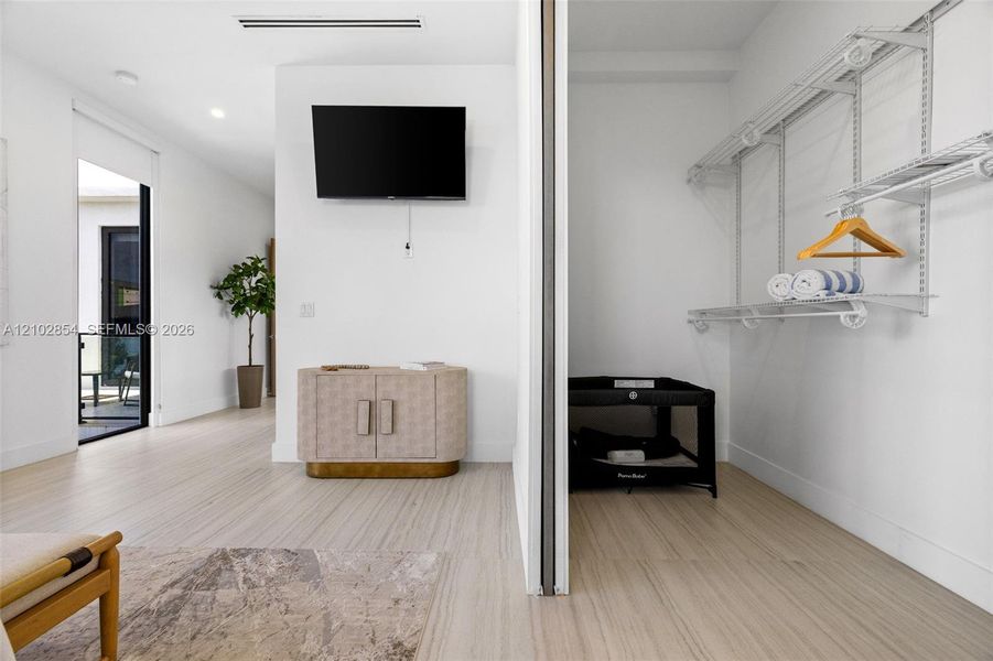 Interior space featuring wood-finish flooring, recessed lighting, white walls, and a walk-in closet equipped with metal shelving