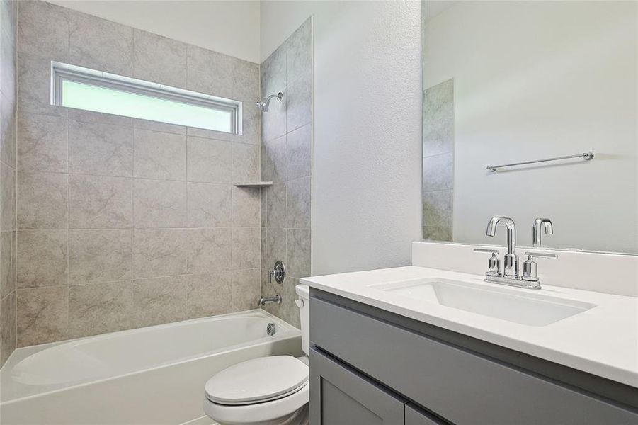 Full bathroom featuring vanity, tiled shower / bath, and toilet