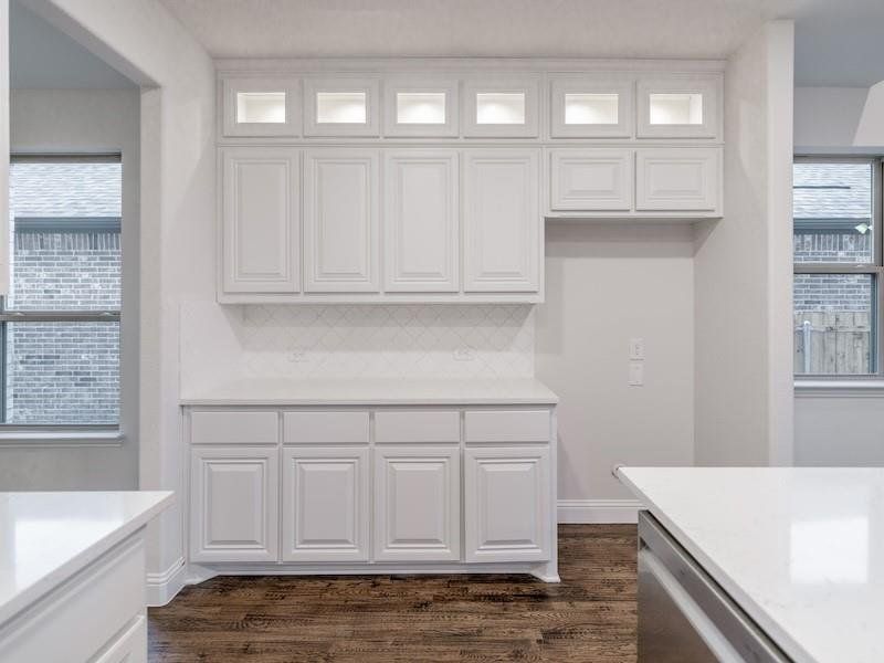 Kitchen featuring white cabinetry, stainless steel dishwasher, and decorative backsplash