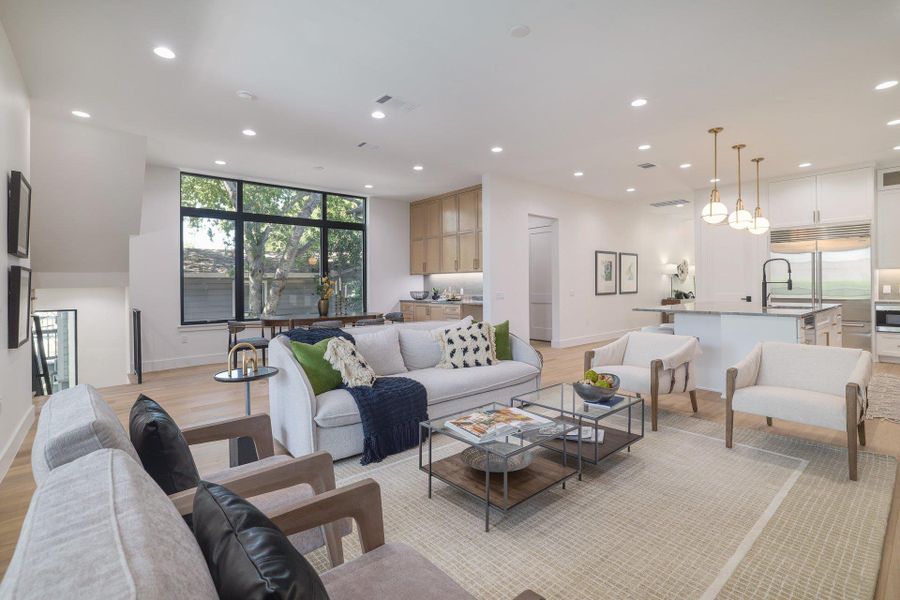 Open-concept living area with light wood-finish flooring, recessed lighting, and a large multi-pane window