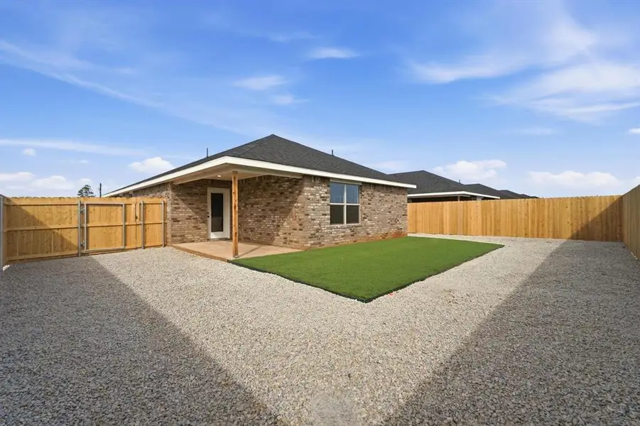 Back of house with brick siding, a fenced backyard, and a patio area