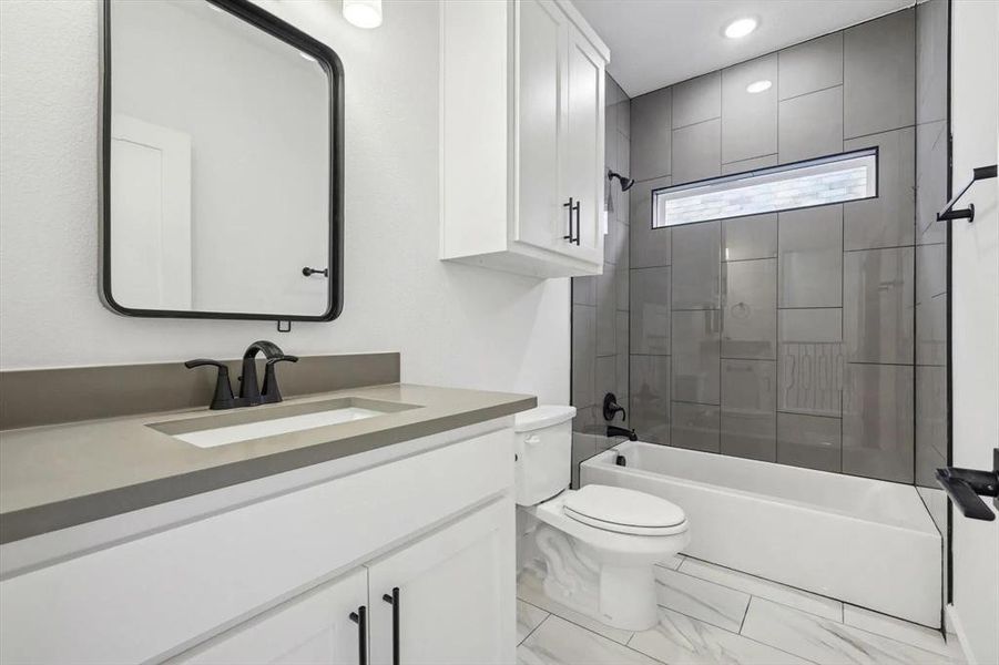 Bathroom featuring vanity, marble look tiles, bathtub / shower combination, and recessed lighting