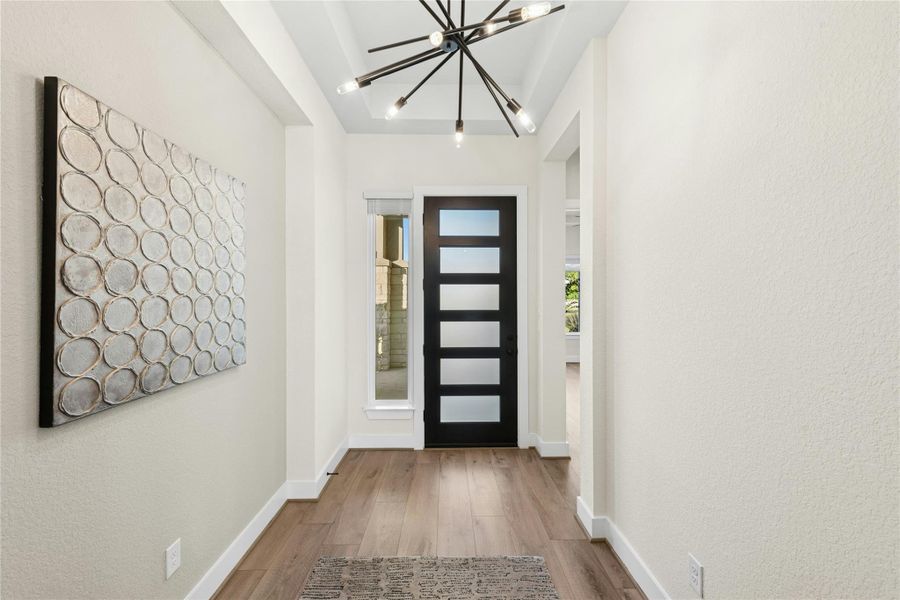 Foyer featuring wood finished floors, a chandelier, and a textured wall Foyer featuring wood finished floors, a chandelier, and a textured wall