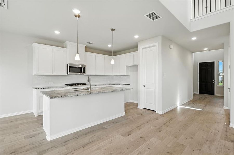 Kitchen featuring light stone countertops, white cabinetry, decorative backsplash, pendant lighting, and recessed lighting Kitchen featuring light stone countertops, white cabinetry, decorative backsplash, pendant lighting, and recessed lighting