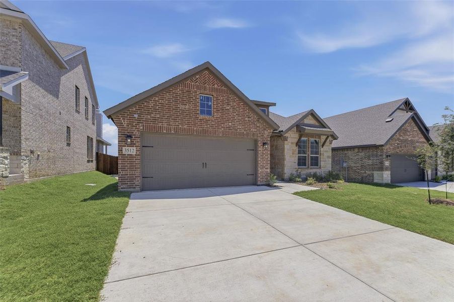 Brick and stone facade residence featuring an attached two-car garage, concrete driveway, and established front landscaping