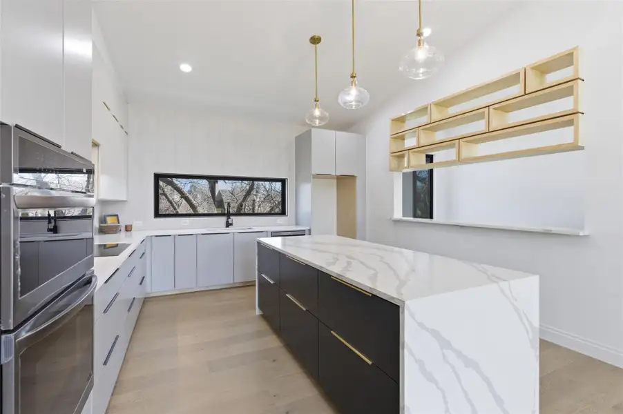 Custom shelving and light fixtures with a large window facing into backyard.