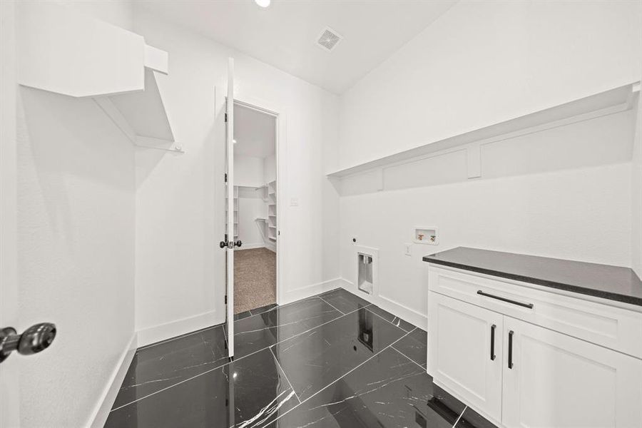 Washroom with electric dryer hookup, washer hookup, baseboards, and dark marble finish flooring Washroom with electric dryer hookup, washer hookup, baseboards, and dark marble finish flooring