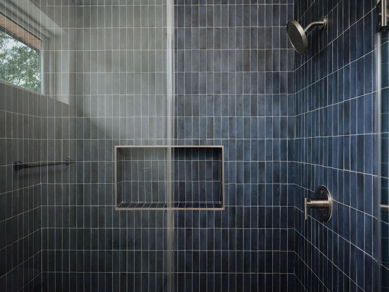 Shower enclosure featuring floor-to-ceiling vertical tile, a built-in niche, and a brushed nickel shower head