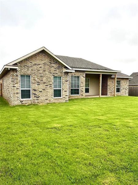 Brick veneer exterior with a covered patio and expansive green lawn Brick veneer exterior with a covered patio and expansive green lawn