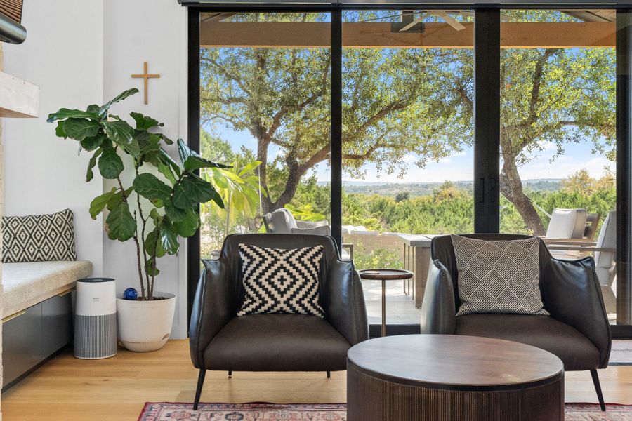 Expansive glass sliding doors open to an outdoor space and distant tree-lined scenery
