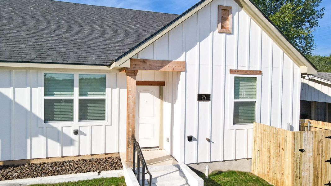 Doorway to property with board and batten siding and roof with shingles
