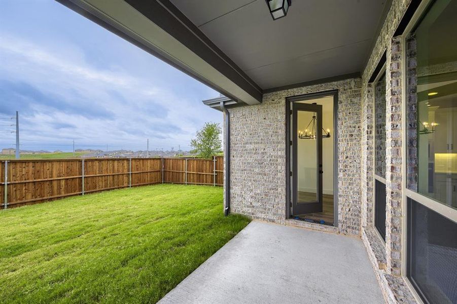 Covered patio with a concrete surface, light-toned brick exterior, and a glass-paned door
