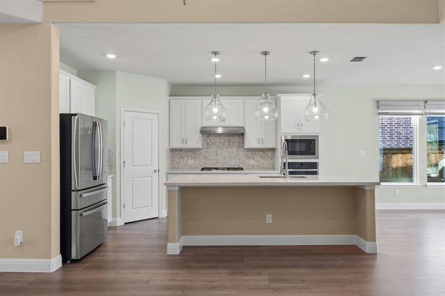 Kitchen with stainless steel appliances, a kitchen island with sink, white cabinetry. Island can seat 4-5 counter-stools.