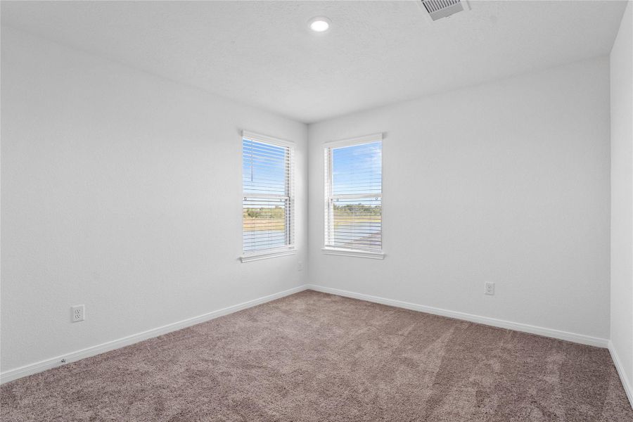 This secondary bedroom offers comfort and style with plush carpeting, neutral paint tones, recessed lighting, large windows with blinds, and a walk-in closet. This secondary bedroom offers comfort and style with plush carpeting, neutral paint tones, recessed lighting, large windows with blinds, and a walk-in closet.