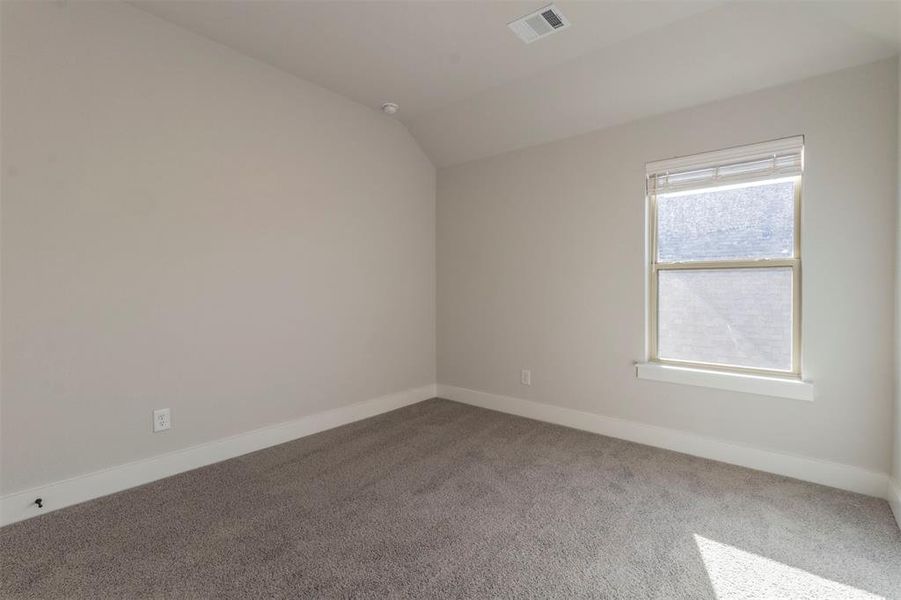 Carpeted spare room featuring lofted ceiling and baseboards