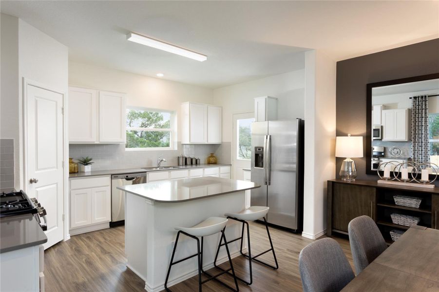 Kitchen featuring stainless steel appliances, white cabinetry, a breakfast bar, backsplash, and a kitchen island