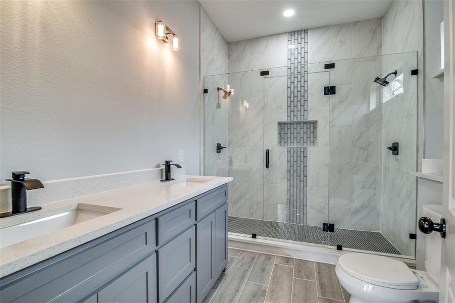 Bathroom with vanity, an enclosed shower, and toilet