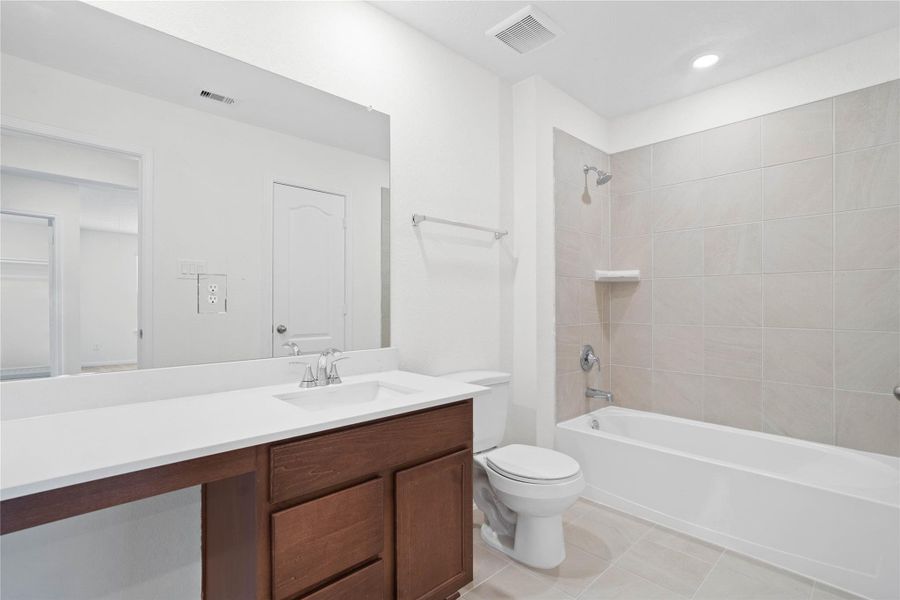 The secondary bathroom showcases tile flooring, a bath/shower combo with Daltile tile surround, a vanity with knee space, a stunning light countertop, a stylish mirror, sleek fixtures, and contemporary finishes throughout. The secondary bathroom showcases tile flooring, a bath/shower combo with Daltile tile surround, a vanity with knee space, a stunning light countertop, a stylish mirror, sleek fixtures, and contemporary finishes throughout.