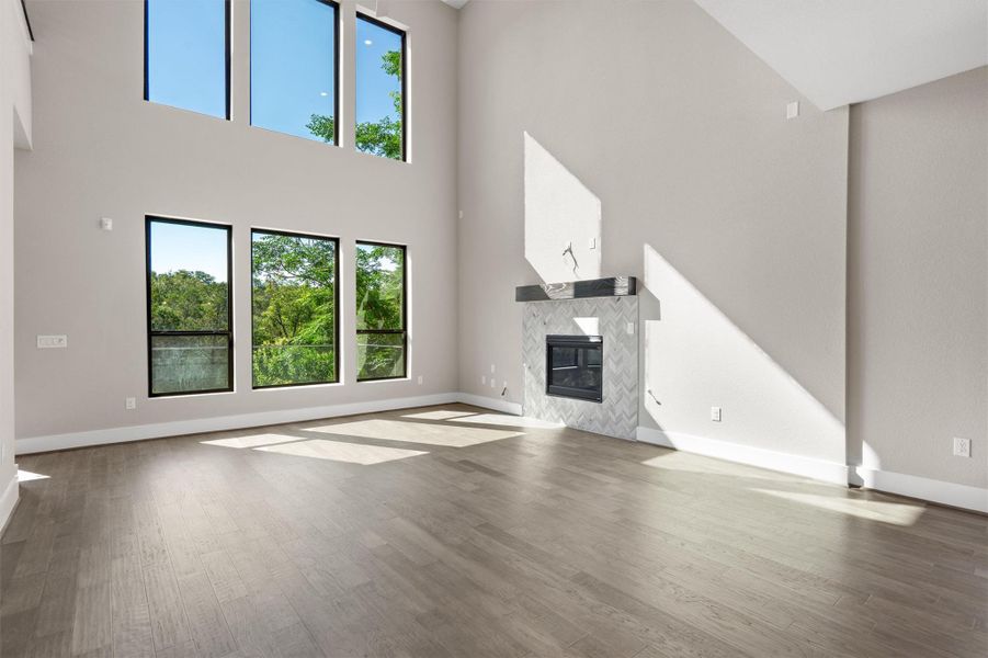 Sun-filled living area featuring soaring ceilings, wide plank flooring, and a contemporary fireplace. Sun-filled living area featuring soaring ceilings, wide plank flooring, and a contemporary fireplace.