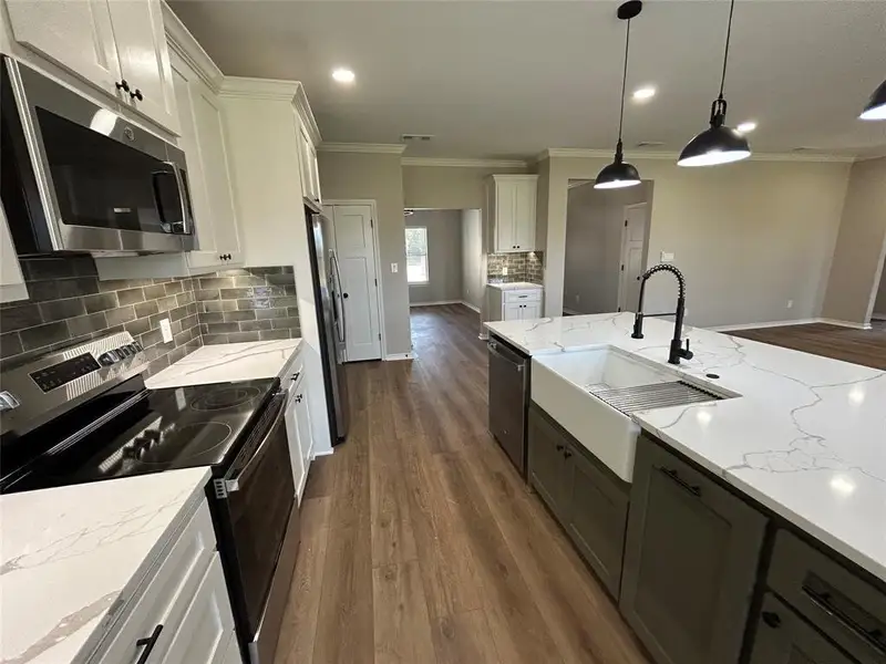 Kitchen with appliances with stainless steel finishes, backsplash, dark wood finished floors, white cabinets, and crown molding