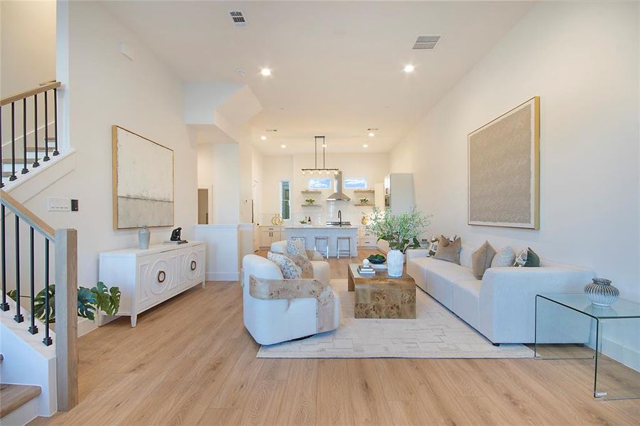 Living room with stairs, light wood-style flooring, and recessed lighting Living room with stairs, light wood-style flooring, and recessed lighting