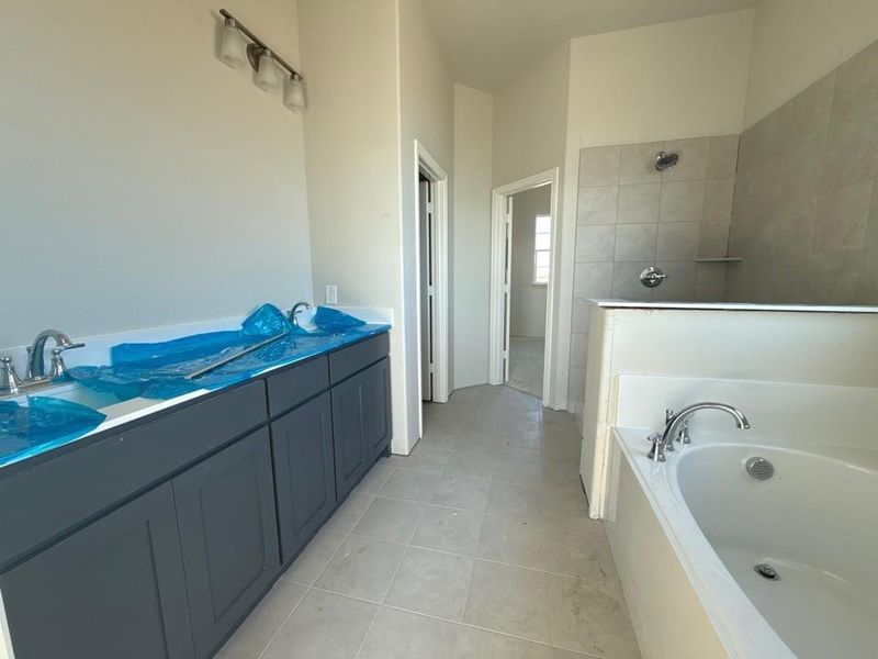 Bathroom with a bath, walk in shower, vanity, and light tile patterned floors