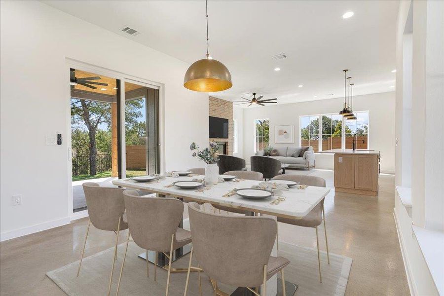 Dining space featuring a fireplace, a ceiling fan, recessed lighting, and concrete flooring