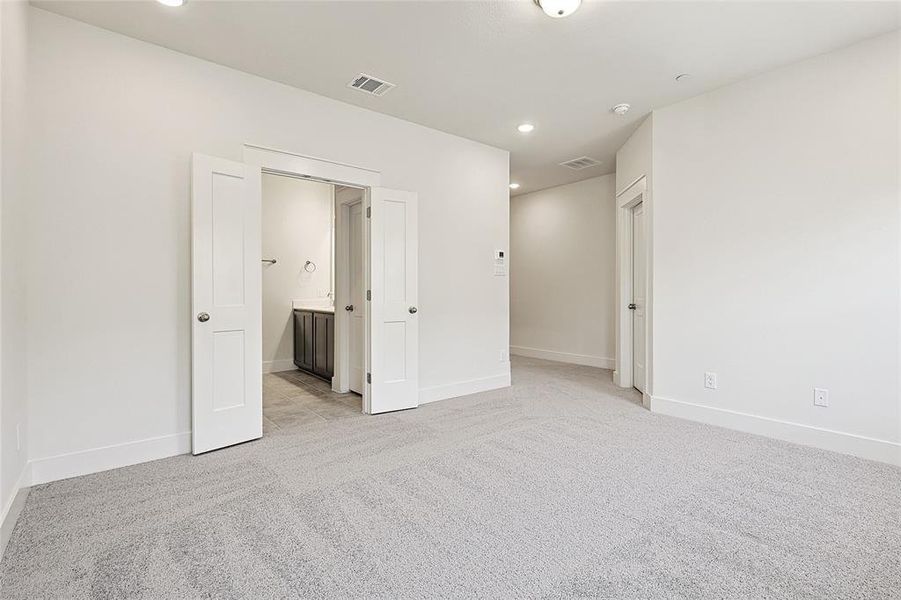 Unfurnished bedroom featuring light carpet and ensuite bathroom