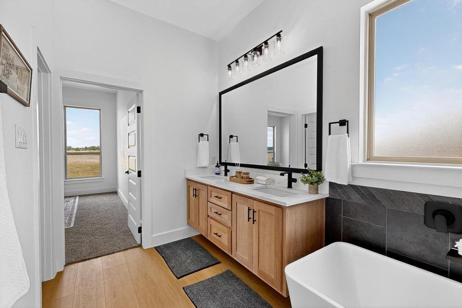Bathroom with wood finished floors, a freestanding bath, and double vanity