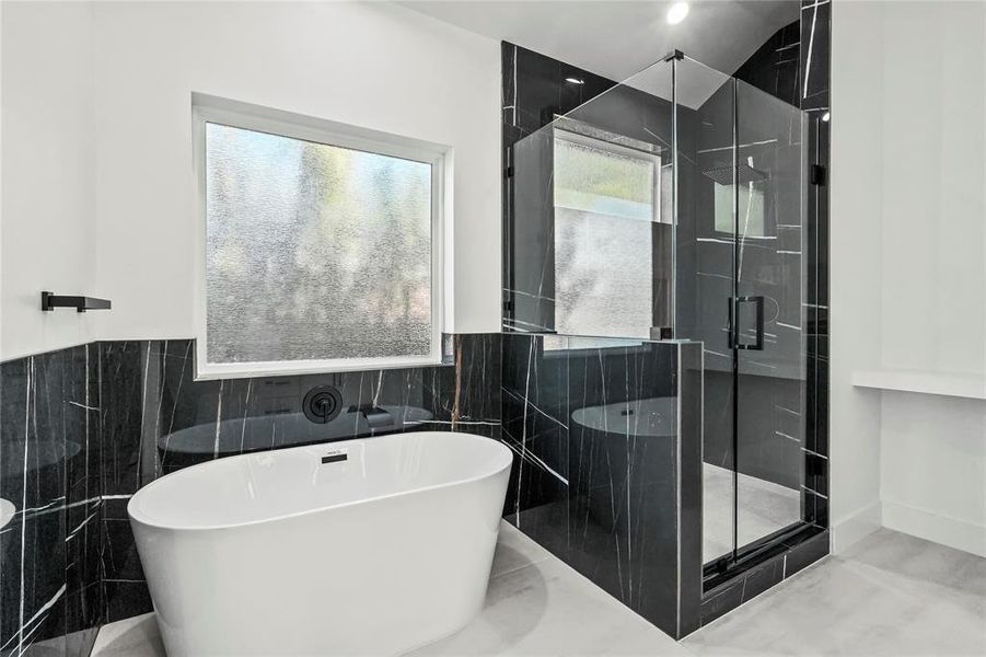 Bathroom with tile walls, a soaking tub, a marble finish shower, and a wainscoted wall