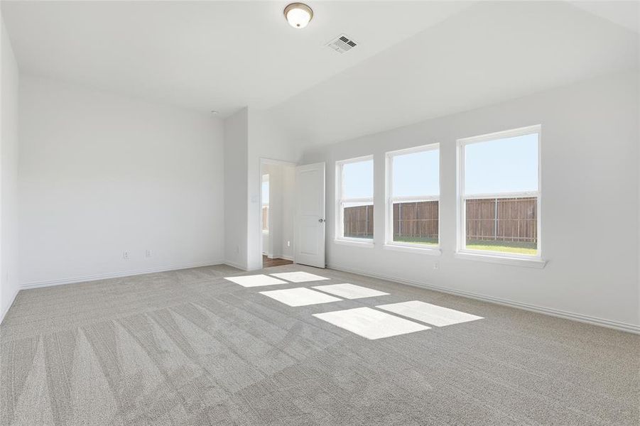 Spacious room featuring vaulted ceilings, light-colored carpeting, and three large windows