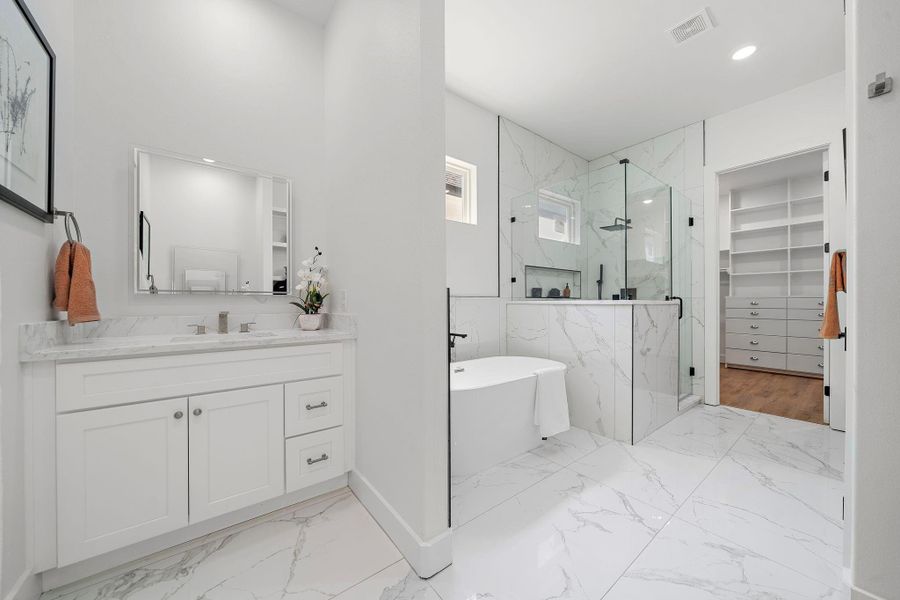 This modern bathroom features a sleek design with a spacious glass shower, freestanding tub, and a white vanity with quartz countertops. The bright space offers ample storage with a large walk-in closet with custom built shelves. This modern bathroom features a sleek design with a spacious glass shower, freestanding tub, and a white vanity with quartz countertops. The bright space offers ample storage with a large walk-in closet with custom built shelves.