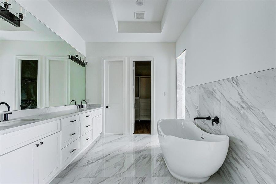 What a stunning ensuite bathroom! Features include dual vanities, crisp white cabinets with coordinating white countertops, oil rubbed bronze fixtures, a large frameless mirror with vanity lighting, an oversized walk-in shower, soaking tub, linen closet, and privately tucked away commode.