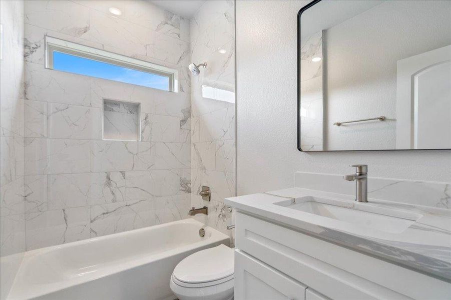 A beautifully crafted bathroom featuring a framed mirror and a window that illuminates the bathtub/shower combo. A beautifully crafted bathroom featuring a framed mirror and a window that illuminates the bathtub/shower combo.