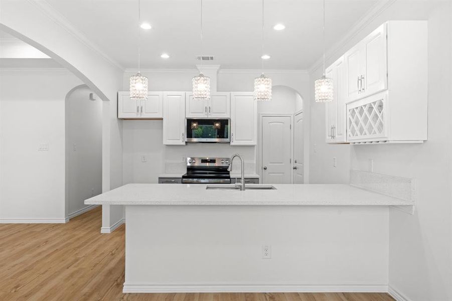 Kitchen with stainless steel appliances, arched walkways, light wood-style flooring, white cabinetry, and recessed lighting Kitchen with stainless steel appliances, arched walkways, light wood-style flooring, white cabinetry, and recessed lighting