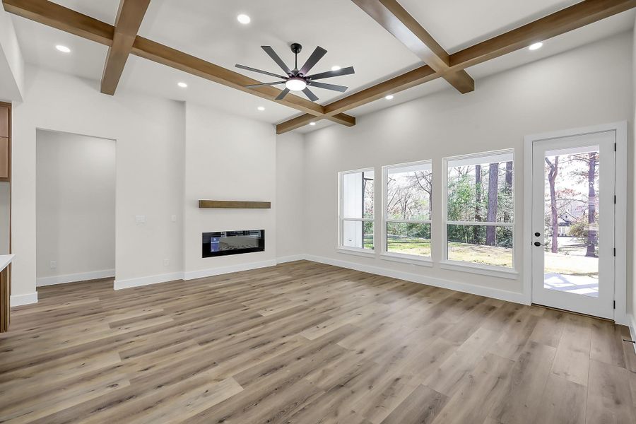 The large, open living room features wood toned beams, cosy electric fireplace and pretty views of the backyard.